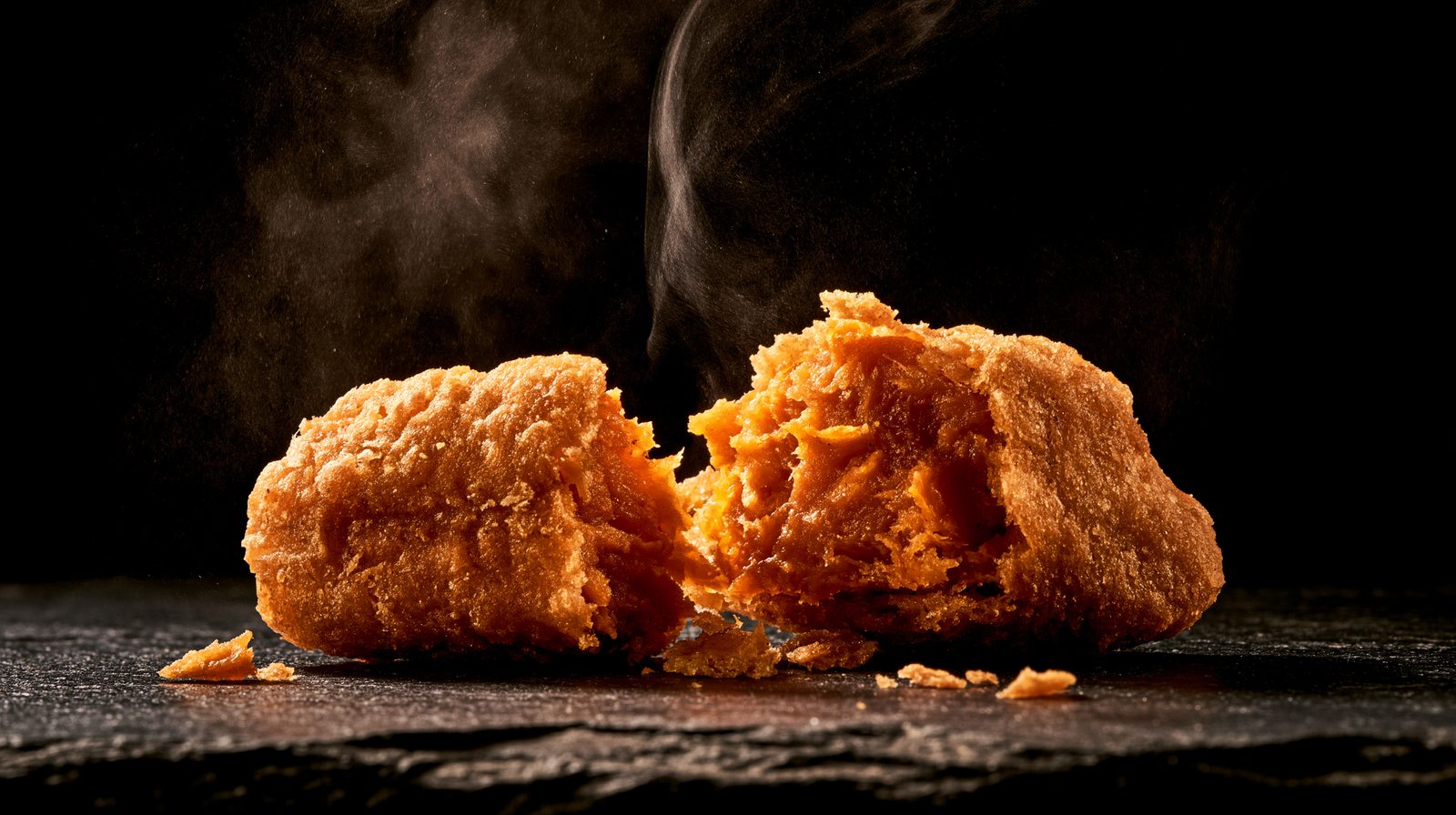 A fried cutlet broken open, steam rising, crust in sharp focus
